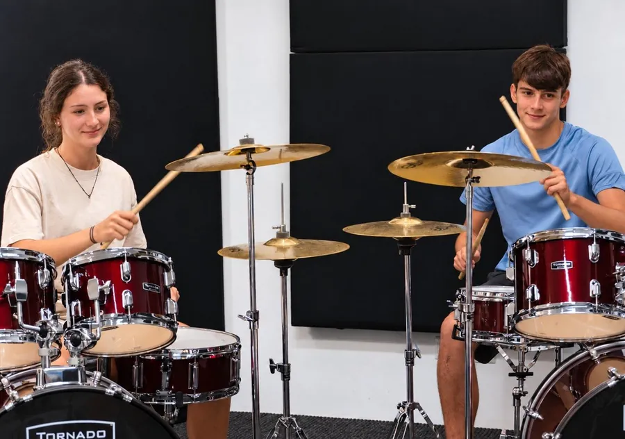 Dos alumnos tocando la batería juntos en clase